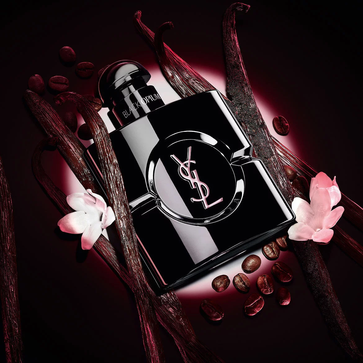 Flacon Black Opium Le Parfum noir brillant, entoure de gousses de vanille sombre et de jasmin blanc.