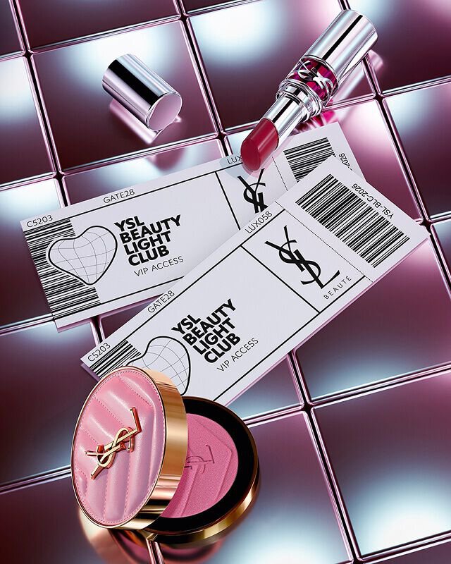 Rouge a levres Loveshine teinte Make Me Blush et deux invitations VIP YSL Beauty Light Club sur un fond en carrelage reflechissant.