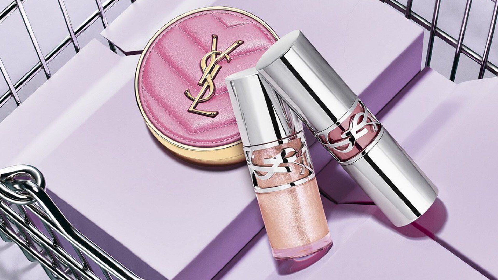 Poudrier rose et rouges a levres YSL dans un panier argente.