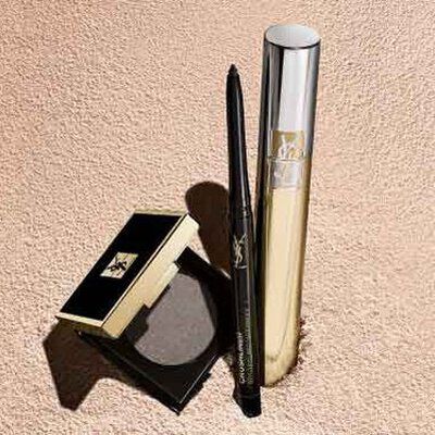 A flat lay of beauty products, including an eyeshadow palette, an eyeliner, and a makeup brush, set against a soft, textured beige background.