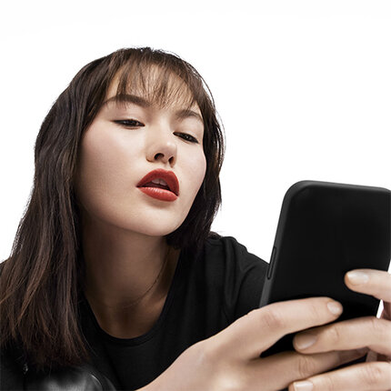 Femme regardant son telephone avec des levres rouges et un maquillage elegant.