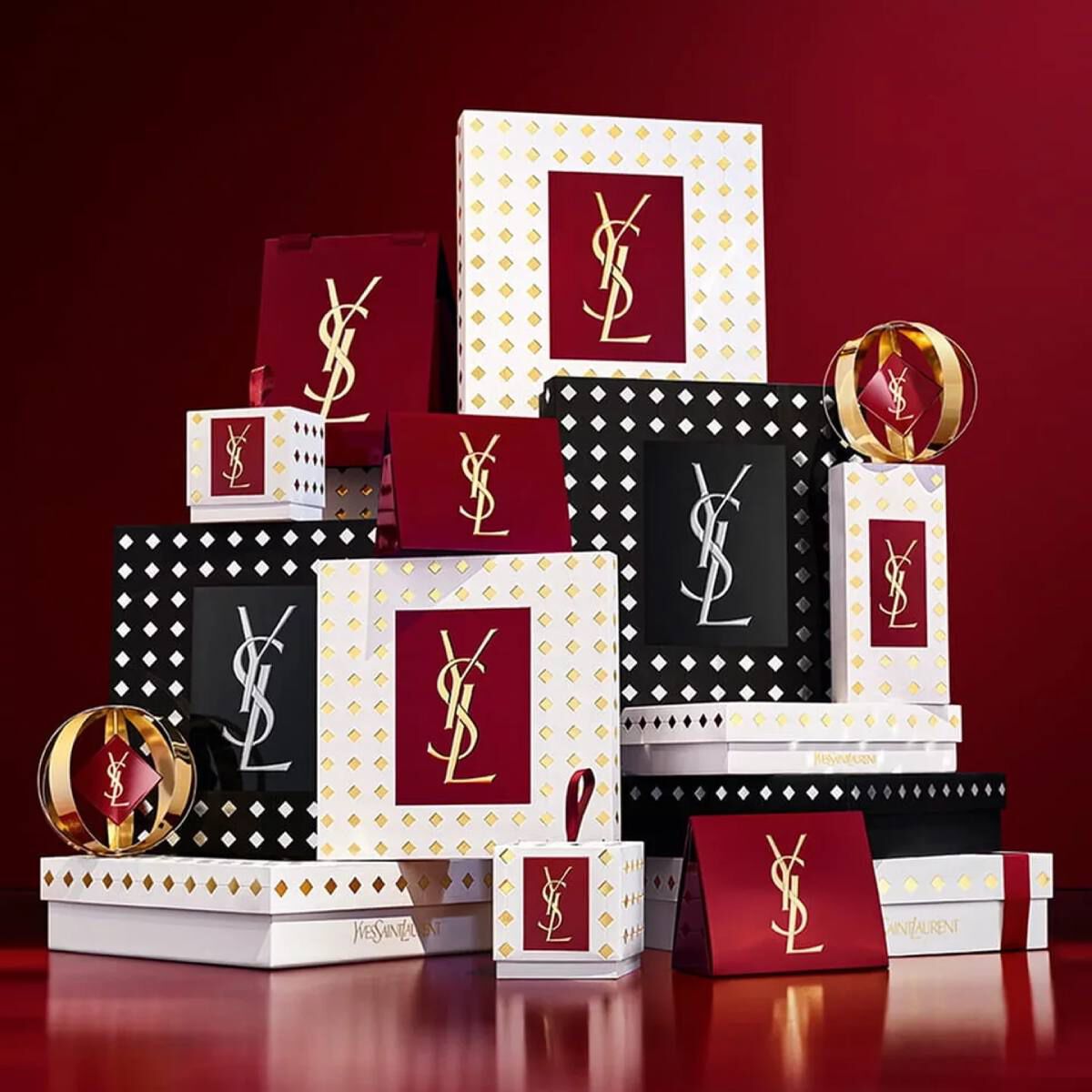 Coffrets cadeaux de la collection de fetes Yves Saint Laurent et produits de beaute de luxe sur fond rouge festif.