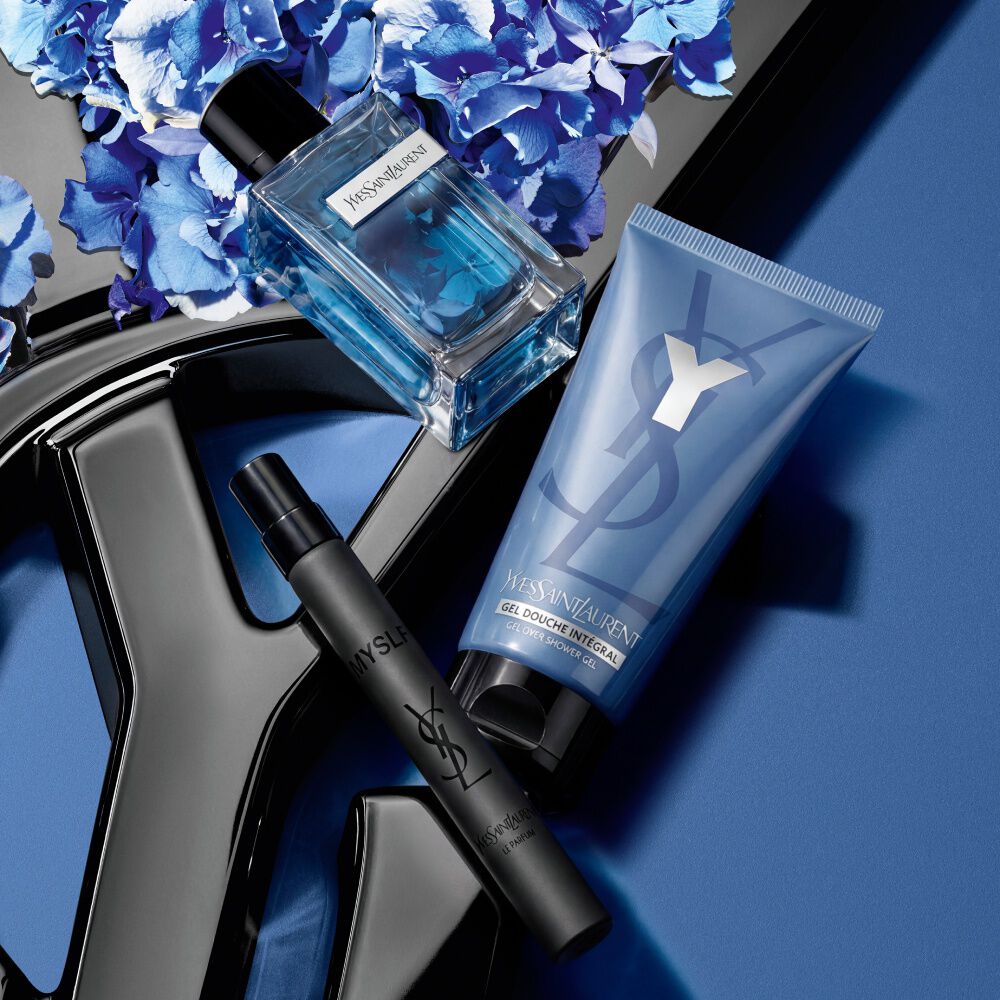 Parfum YSL, spray de voyage et gel douche sur fond bleu fleuri