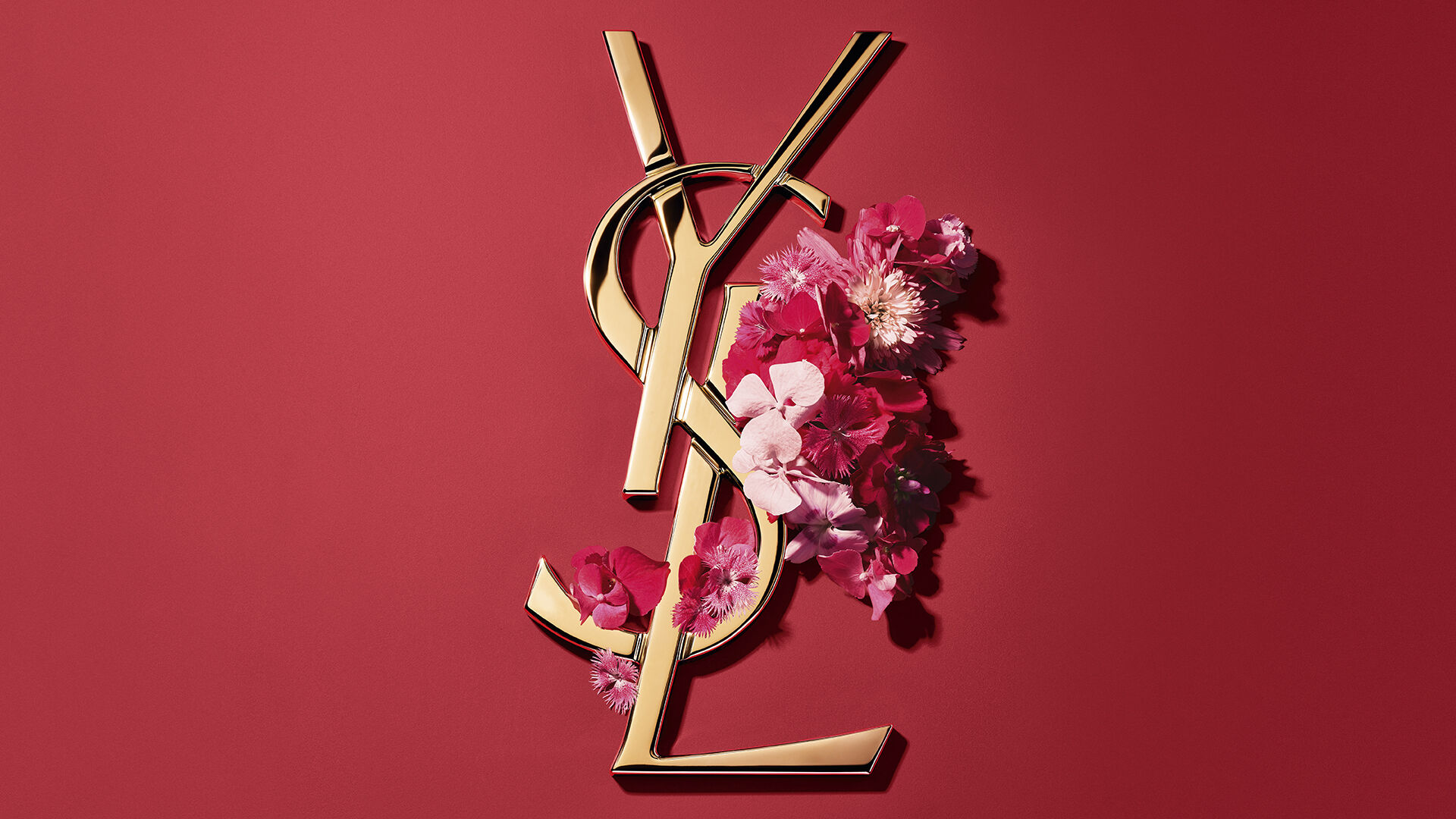 Coffret cadeau YSL rouge avec fleurs roses sur fond rouge.