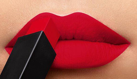 Close-up of bold red lips with a lipstick tube hovering just above them, highlighting the vibrant color and smooth texture.