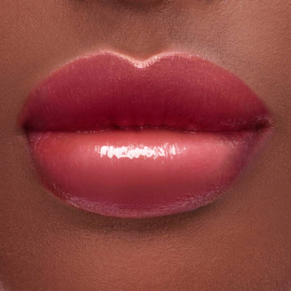 Close-up of a pair of full, glossy lips with a gradient of deep pink to soft nude shades.