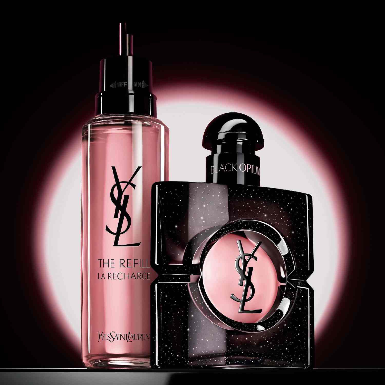 Une main tenant un flacon de recharge dore sur un fond neutre. A gauche, un texte blanc style pinceau indique « Rejoignez le mouvement RECHARGE », et a droite, un flacon de parfum classique YSL Libre en verre avec son logo dore emblematique est presente.