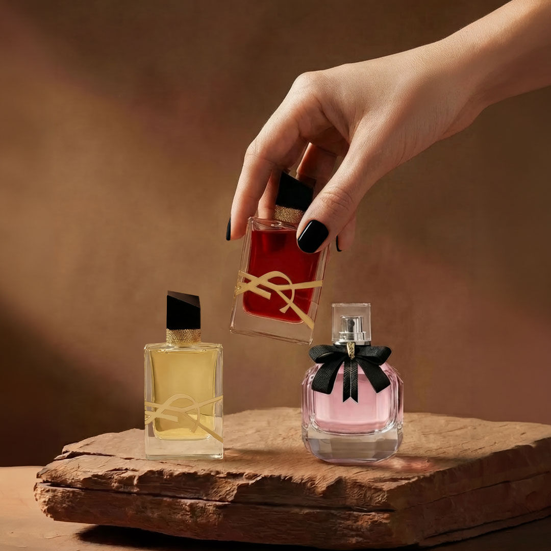 Deux parfums YSL sur une surface de roche brune texturee.