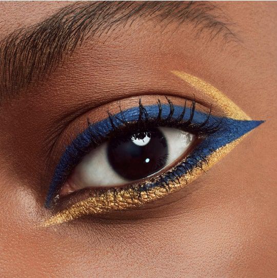 A close-up of an eye featuring bold blue and gold eyeliner, with long eyelashes and a smooth skin tone.