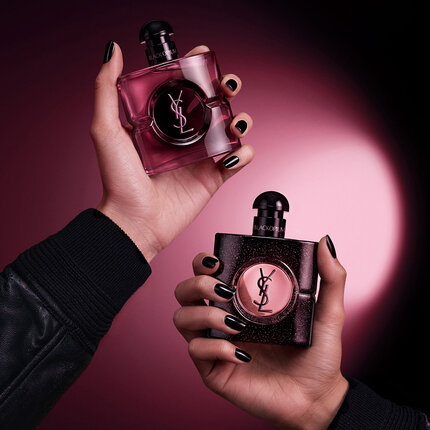 Deux flacons YSL Black Opium sur fond rose avec fleurs et grains de cafe