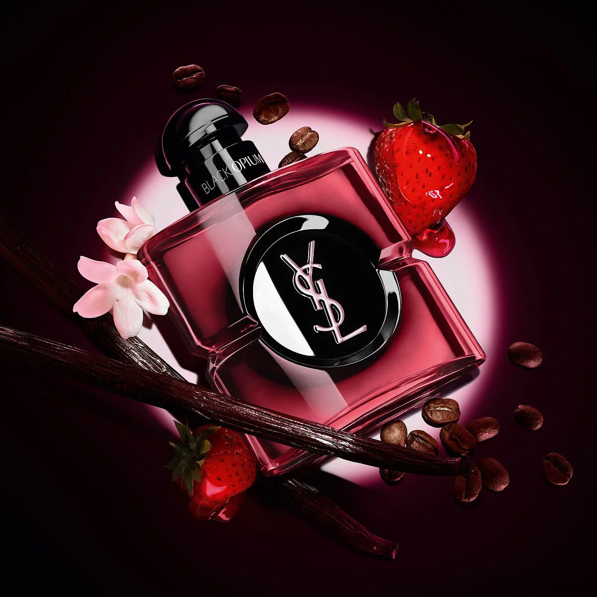 Flacon Black Opium Eau de Parfum Pink Glaze entoure de fraises fraiches, de gousses de vanille, de grains de cafe et de jasmin.
