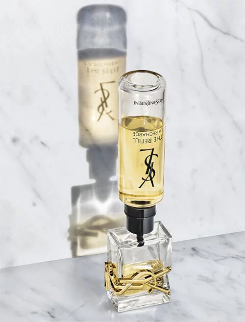 Flacon de parfum YSL pose sur un fond en marbre, avec une ombre projetee.