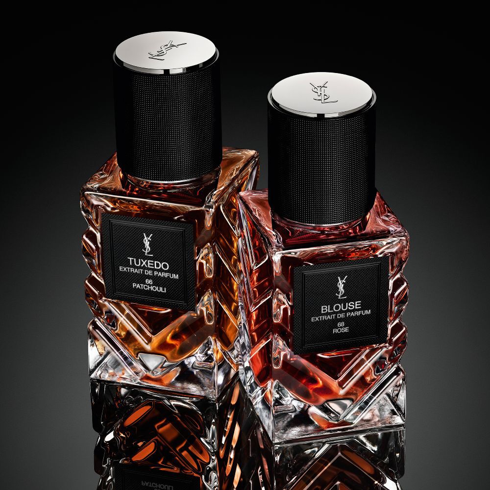 Une collection de flacons de la gamme « Le Vestiaire des Parfums » d'Yves Saint Laurent disposes en losange sur une surface noire reflechissante.