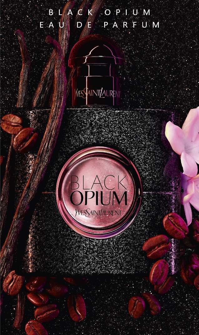 Flacon de parfum "Black Opium" d'Yves Saint Laurent, entoure de grains de cafe, de gousses de vanille et d'une fleur, sur un fond noir.