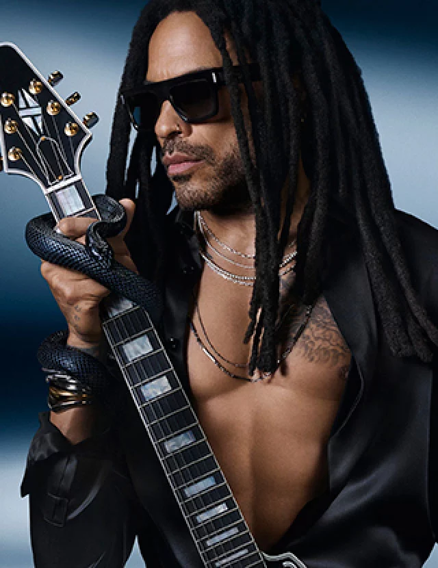Homme aux dreadlocks portant des lunettes de soleil, tenant une guitare electrique et un serpent noir, dans un eclairage dramatique.