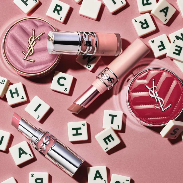 Produits de maquillage YSL et lettres sur fond rose.