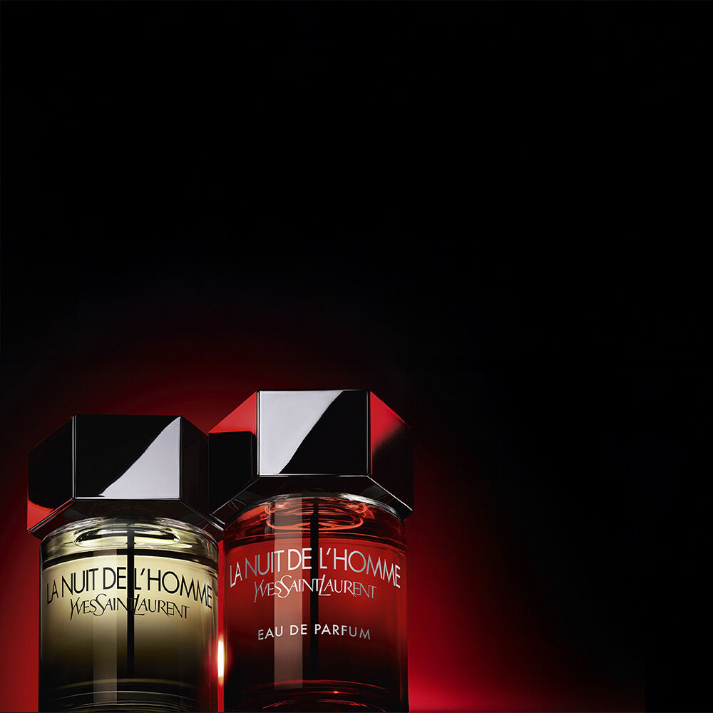 Flacons La Nuit de l’Homme YSL sur fond rouge sombre.