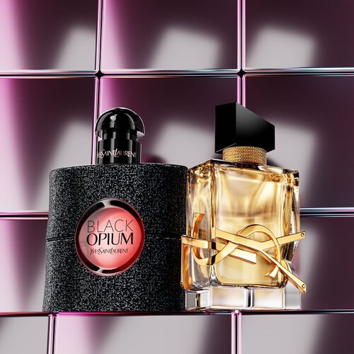 Flacons de parfum YSL disposes sur un piedestal devant un paysage desertique.