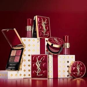 Coffrets cadeaux de la collection de fetes Yves Saint Laurent et produits de beaute de luxe sur fond rouge festif.