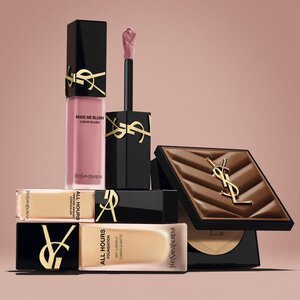 Produits de beaute YSL, dont un blush, un fond de teint et une poudre compacte, sur fond nude.