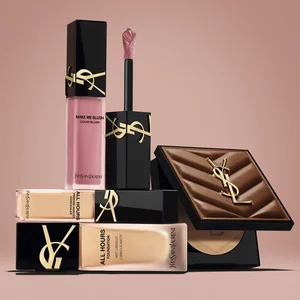 Produits de beaute YSL, dont un blush, un fond de teint et une poudre compacte, sur fond nude.