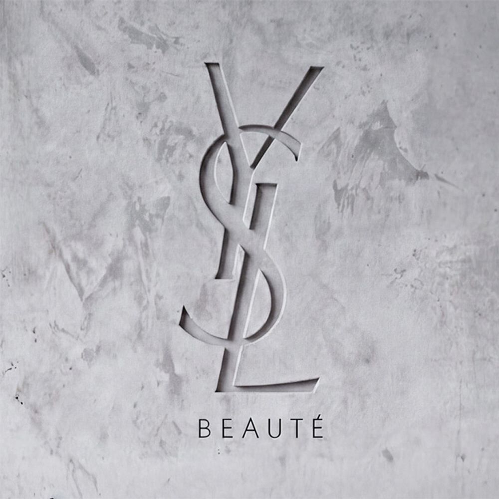 Logo YSL BEAUTE grave dans un mur en beton gris texture.​