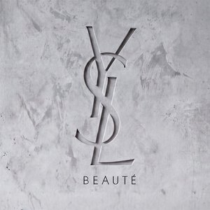 Logo YSL BEAUTE grave dans un mur en beton gris texture.