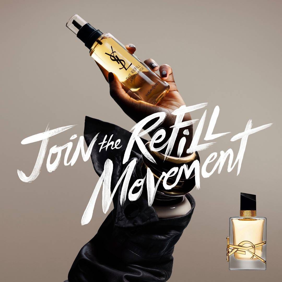 Une main tenant un flacon de recharge dore sur un fond neutre. A gauche, un texte blanc style pinceau indique « Rejoignez le mouvement RECHARGE », et a droite, un flacon de parfum classique YSL Libre en verre avec son logo dore emblematique est presente.​