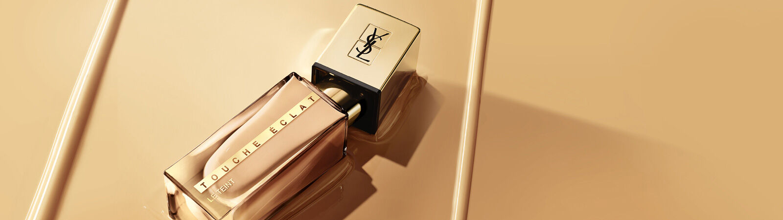 Flacon de parfum Touche Eclat d'Yves Saint Laurent sur un fond dore.