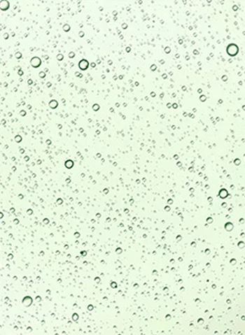 Des gouttes d'eau sur une surface verte, creant un effet de texture et de transparence.