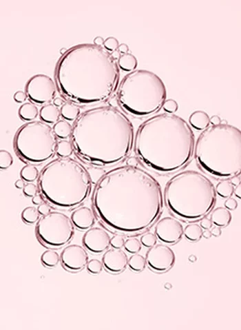 Des bulles transparentes de differentes tailles sur un fond rose.