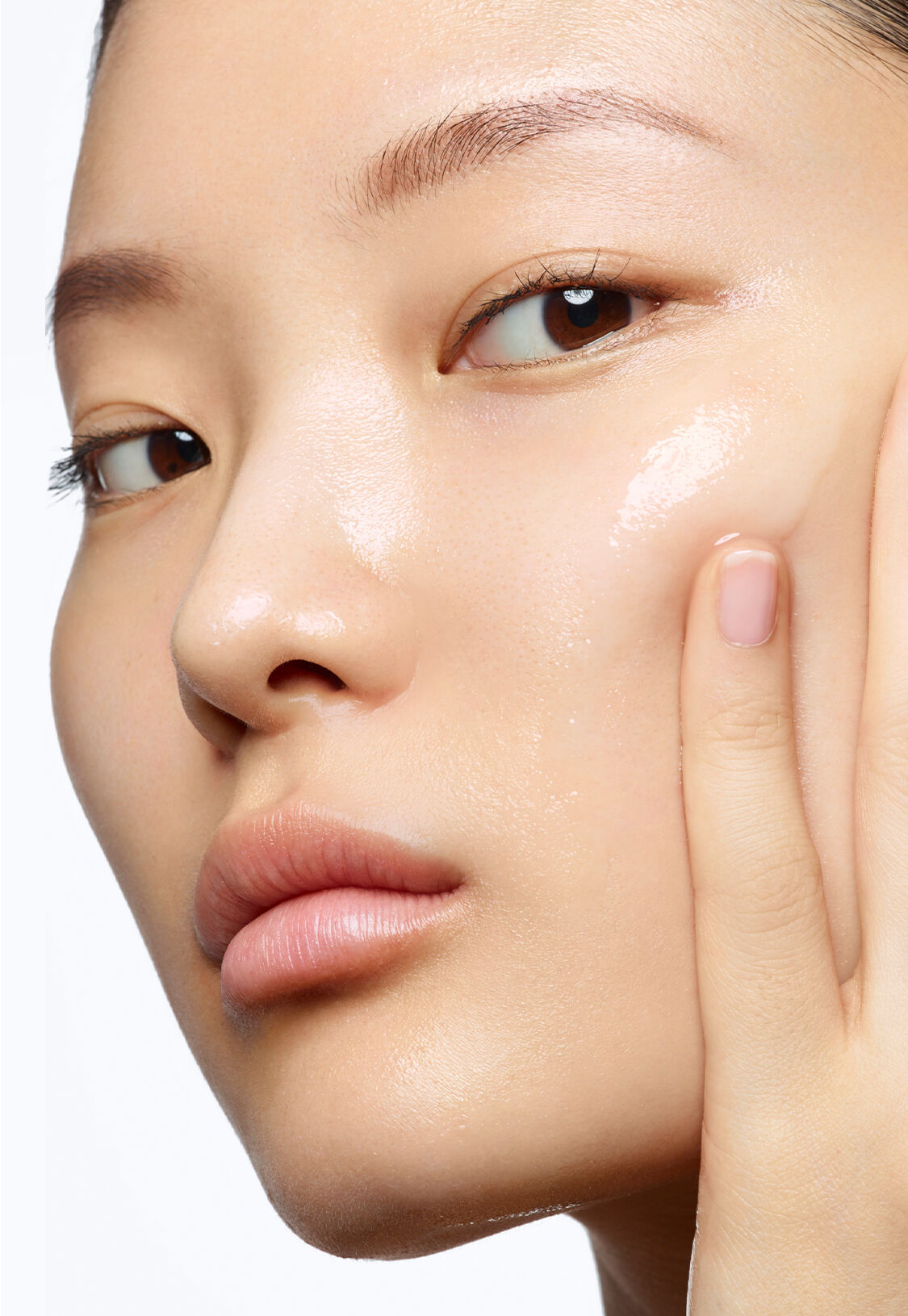 Femme appliquant un soin sur son visage, affichant une peau lumineuse et douce.