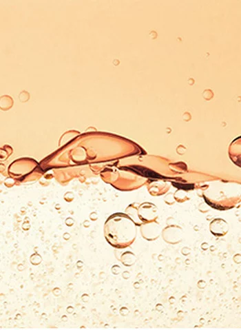 Des bulles d'air flottent dans un liquide de couleur rose pale, creant des ondulations en surface.