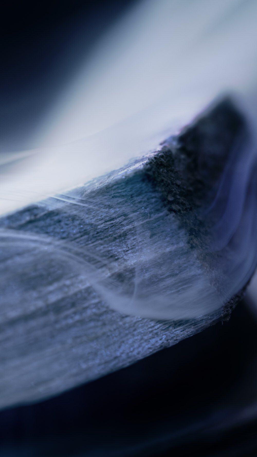 A close-up image showcasing a textured surface with soft, flowing lines in shades of blue and gray, creating an abstract and atmospheric appearance.
