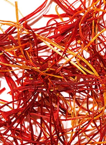 Des filaments de safran rouge et jaune entremeles sur un fond blanc.