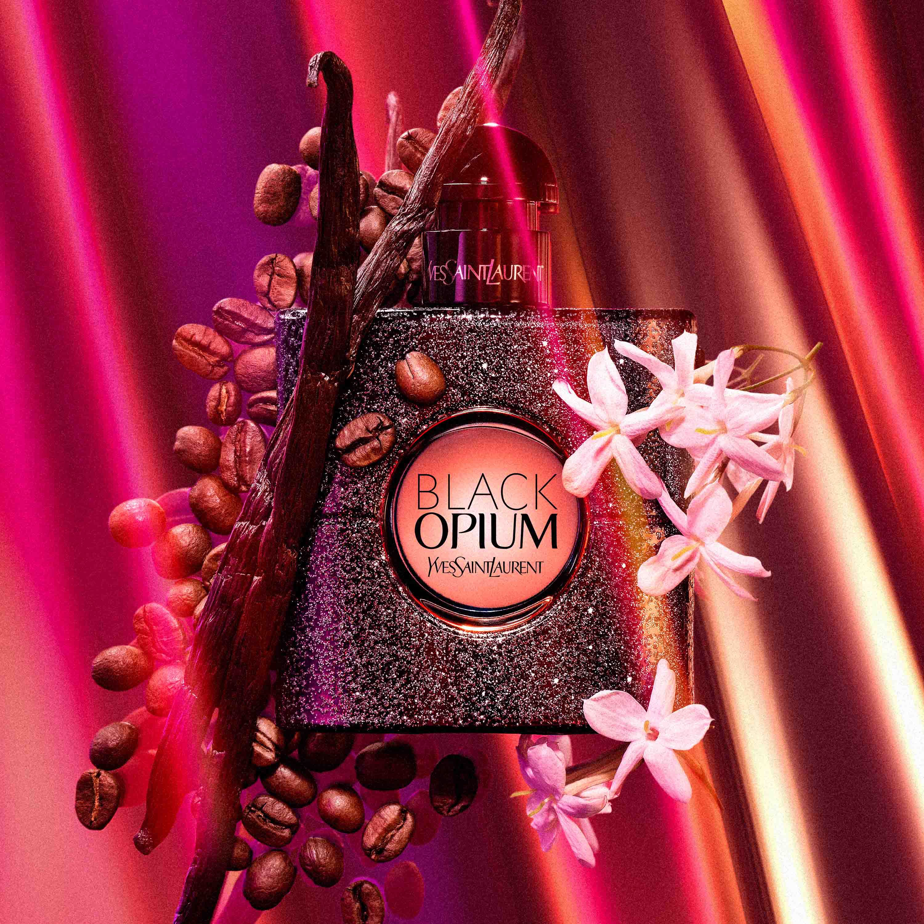 Flacon de parfum Black Opium d'Yves Saint Laurent, entoure de grains de cafe, de fleurs et de batons de vanille, dans un fond aux couleurs vives.