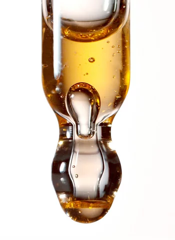 Une pipette contenant un liquide brun dore, avec des bulles d'air a l'interieur.
