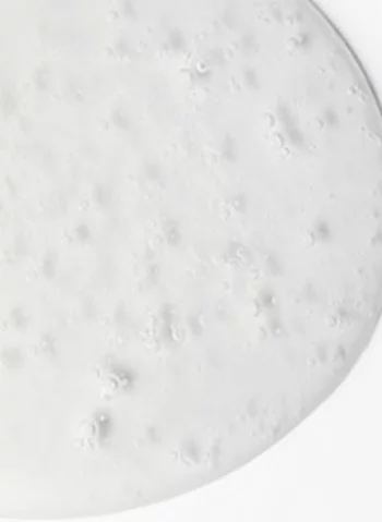 Surface lisse et blanche, legerement texturee avec des petites bulles d'air, ressemblant a une creme ou une pate.