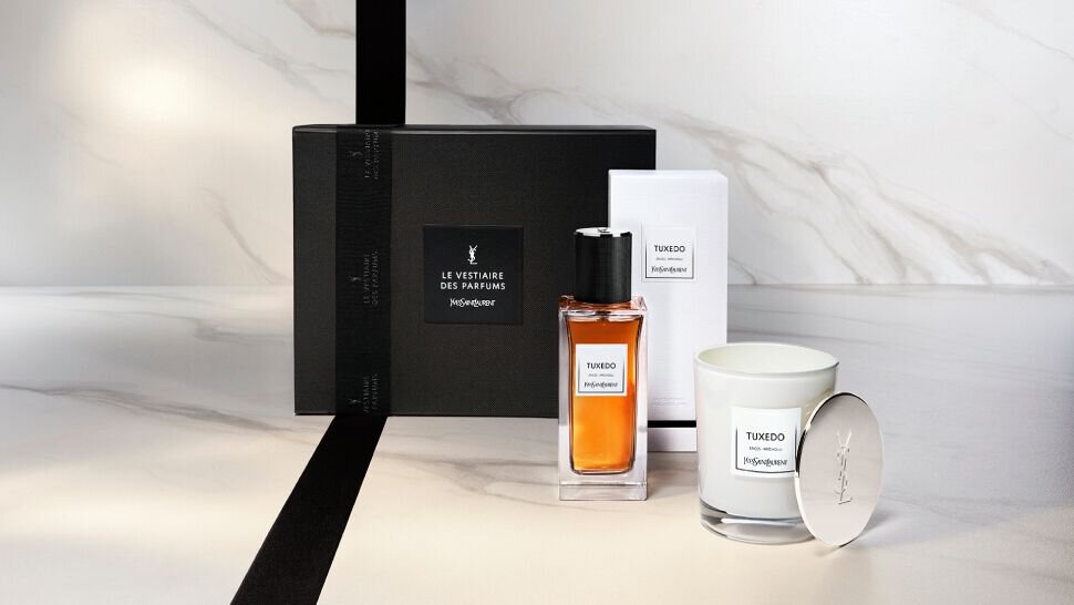 Un ensemble de parfum Tuxedo d'Yves Saint Laurent, comprenant un flacon de parfum et une bougie, presente dans une elegante boite noire sur un fond marbre.