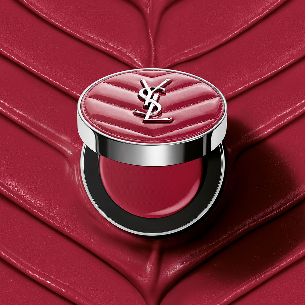 Un boitier ouvert de YSL Make Me Blush Lifted Glow Cream Blush, teinte #44 Nude Lavalliere, pose sur un fond creme texture rose assorti.