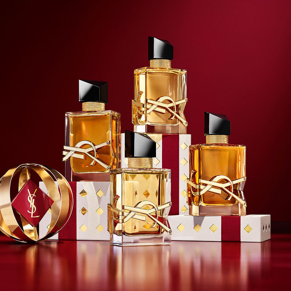Des flacons de parfum YSL LIBRE superposes sur un ecrin de fete aux motifs dores, luxe et subversion.