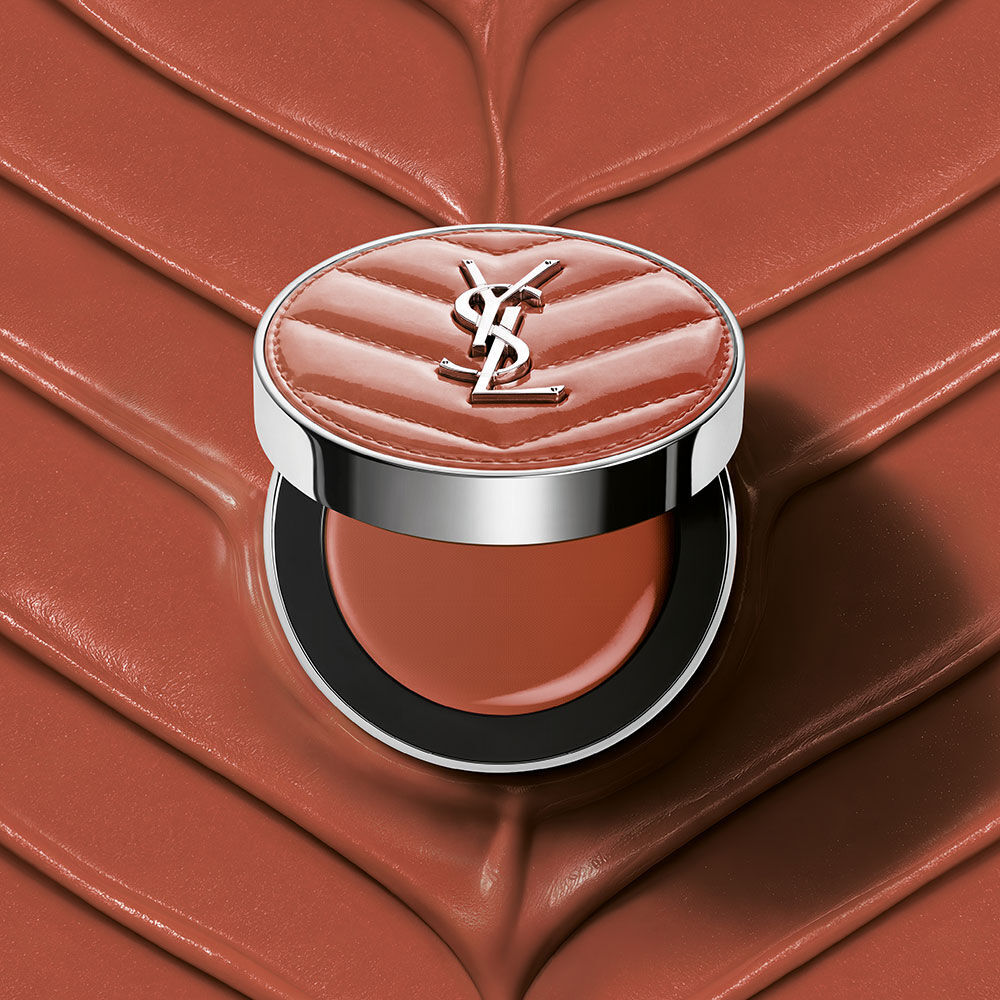 Un boitier ouvert de YSL Make Me Blush Lifted Glow Cream Blush dans la teinte #44 Nude Lavalliere sur un fond creme texture rose assorti.