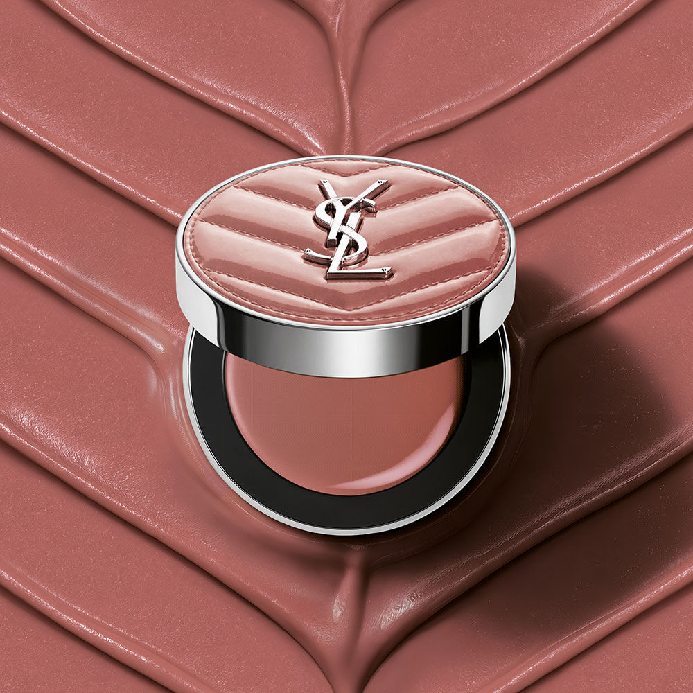 Un boitier ouvert de YSL Make Me Blush Lifted Glow Cream Blush, teinte #44 Nude Lavalliere, pose sur un fond creme texture rose assorti.