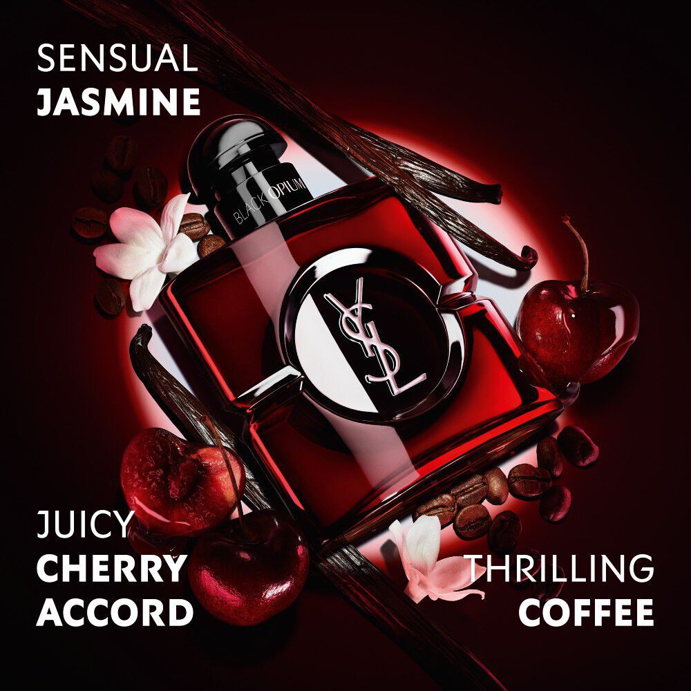 Flacon Black Opium Over Red en laque rouge profond, entoure de cerises rouges fraiches et de grains de cafe, avec mentions.