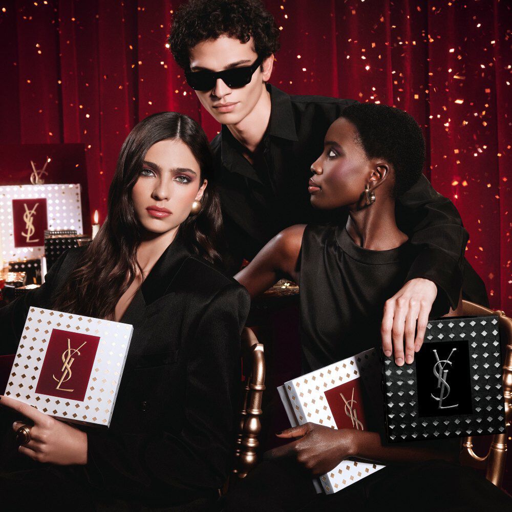 Mannequins reunis, tenant des coffrets cadeaux YSL pour les fetes dans une ambiance luxueuse et electrique.