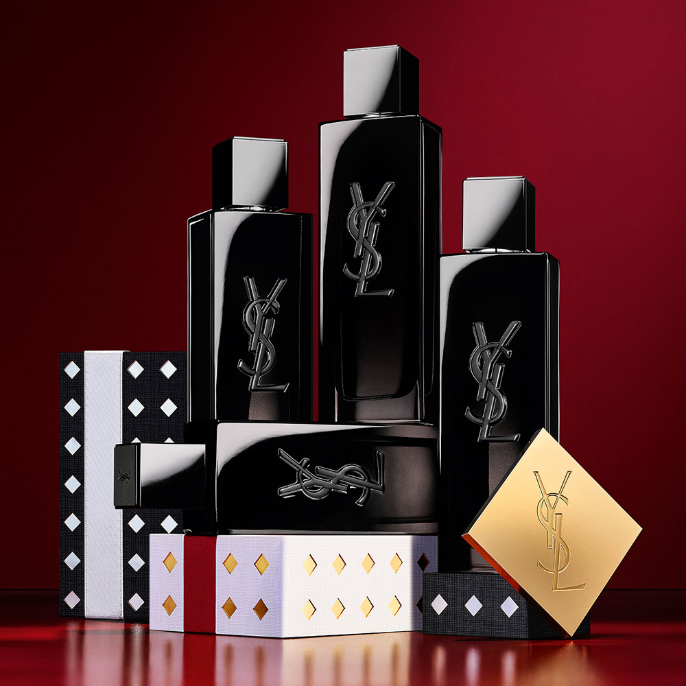 Flacons d'eau de parfum YSL MYSLF empilés sur des coffrets cadeaux de fêtes aux motifs noirs et argentés.