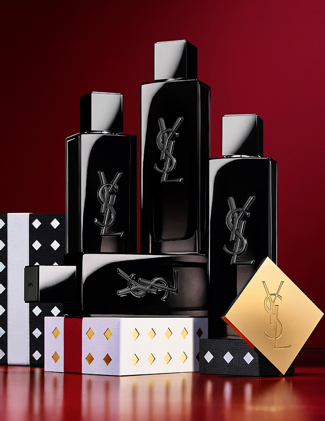 Flacons d'eau de parfum YSL MYSLF empilés sur des coffrets cadeaux de fêtes aux motifs noirs et argentés.