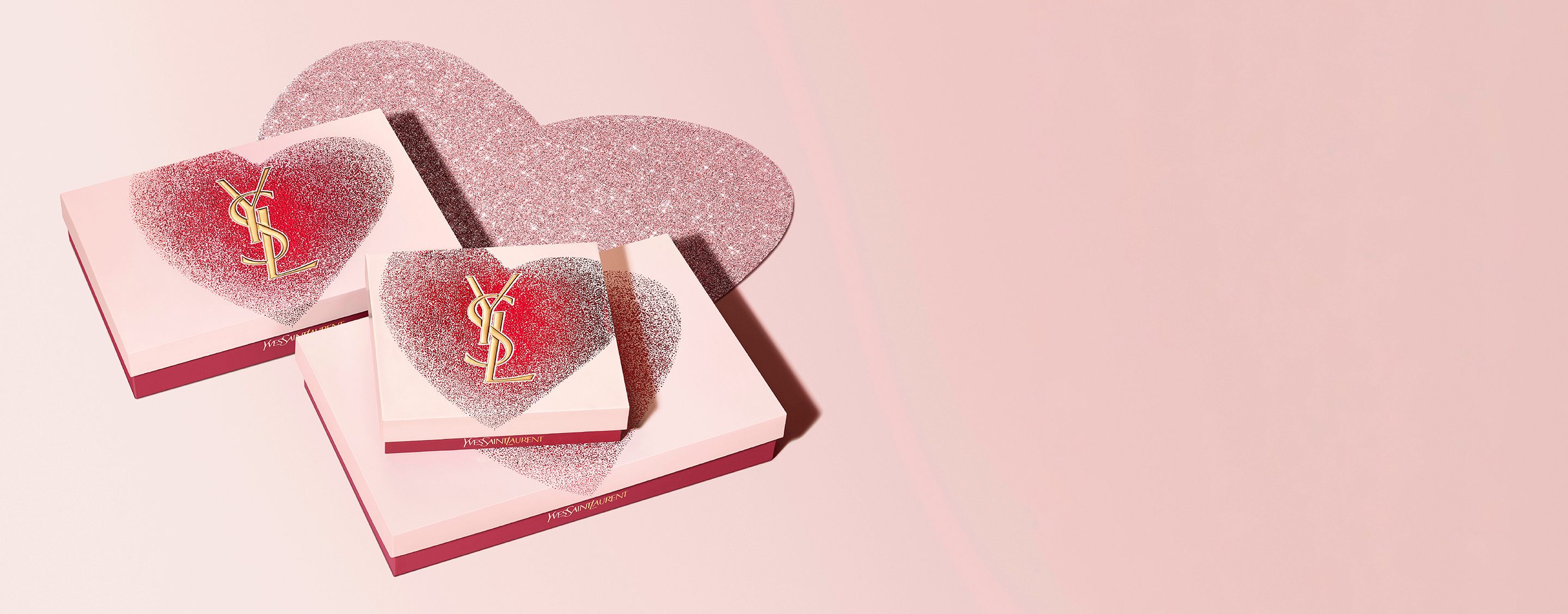 Coffrets cadeaux de la Saint-Valentin YSL Beauty dans des boîtes en forme de cœur avec logo YSL doré, présentant un design rouge et rose scintillant.