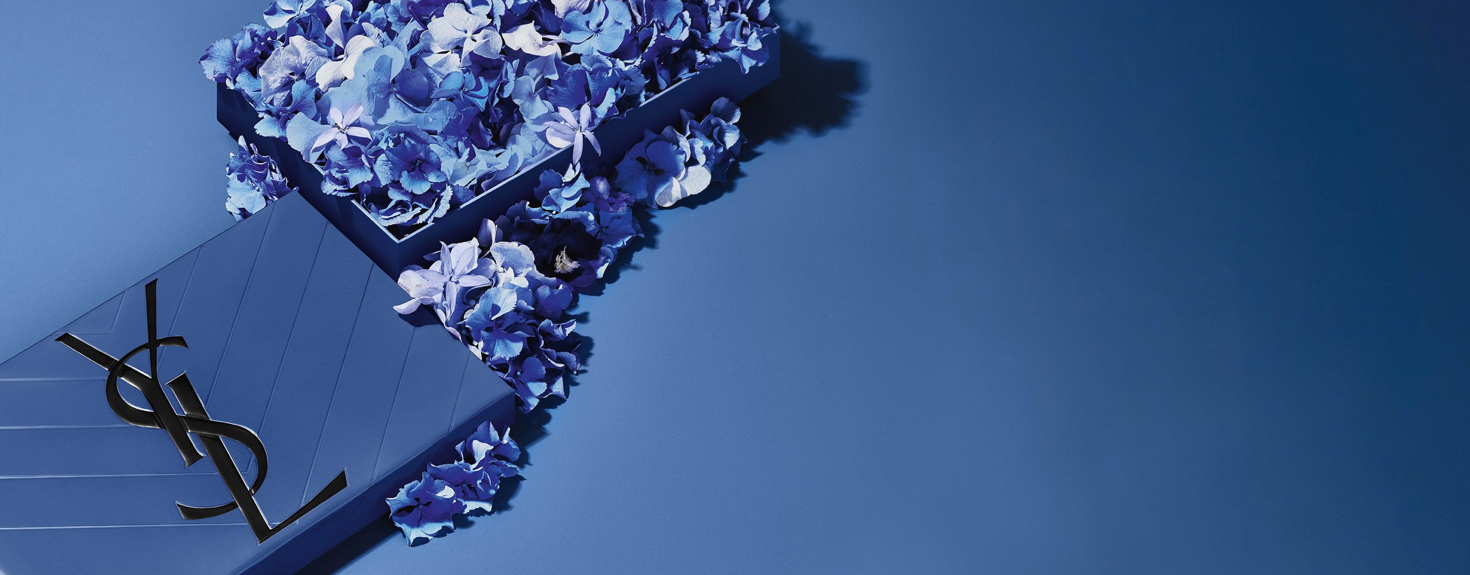 Coffret cadeau bleu YSL pour la fête des Pères, arborant l'iconique logo Cassandre, agrémenté d'une profusion de délicats accents floraux bleus.