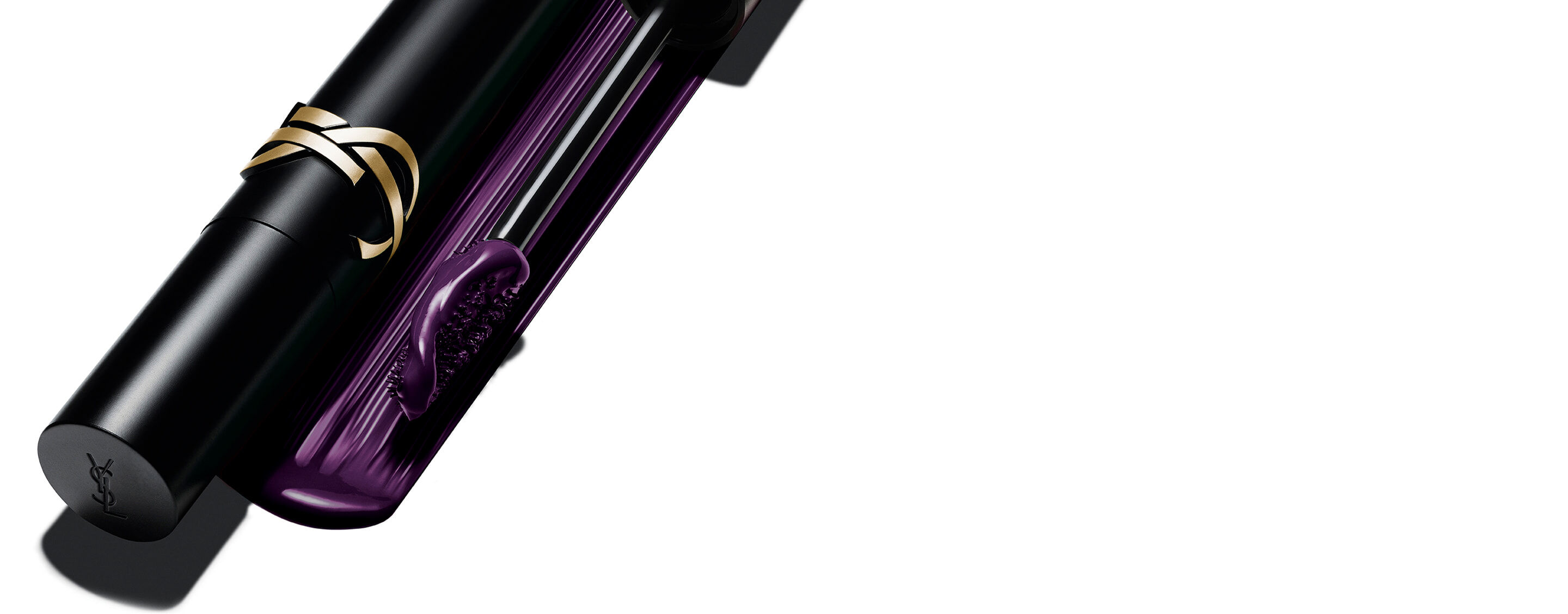 Mascara Lash Clash d'Yves Saint Laurent en teinte prune, avec son tube noir au logo YSL doré et sa brosse révélant la texture violette.